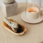 A peaceful aromatherapy scene featuring a burning candle and sage on a beige tablecloth.